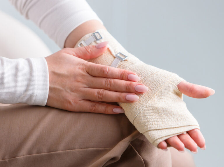 Fotografia przedstawia zabieg chirurgiczny cieśni nadgarstka wykonywany przez doświadczonego chirurga w sterylnych warunkach. Na zdjęciu widać precyzyjne nacięcie w obszarze nadgarstka, umożliwiające odciążenie nerwu pośrodkowego. Specjalistyczne narzędzia oraz zespół medyczny świadczą o wysokim standardzie i dokładności procedury, mającej na celu przywrócenie sprawności ręki.