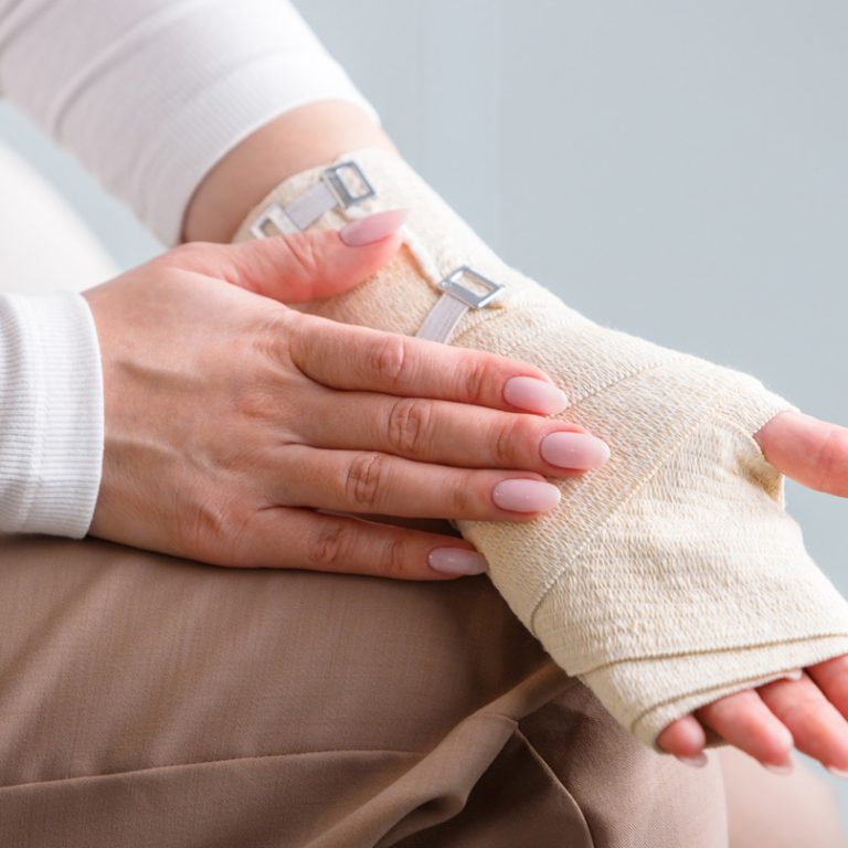 Fotografia przedstawia zabieg chirurgiczny cieśni nadgarstka wykonywany przez doświadczonego chirurga w sterylnych warunkach. Na zdjęciu widać precyzyjne nacięcie w obszarze nadgarstka, umożliwiające odciążenie nerwu pośrodkowego. Specjalistyczne narzędzia oraz zespół medyczny świadczą o wysokim standardzie i dokładności procedury, mającej na celu przywrócenie sprawności ręki.