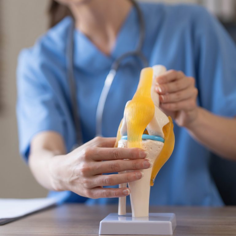 Fotografia przedstawia rekonstrukcję więzadła – zaawansowany zabieg chirurgiczny wykonywany w celu przywrócenia stabilności i funkcji uszkodzonego stawu. Na zdjęciu widoczny jest chirurg w trakcie precyzyjnego operowania stawu kolanowego z użyciem specjalistycznych narzędzi. Sterylne otoczenie sali operacyjnej oraz ekran monitorujący przebieg zabiegu podkreślają profesjonalizm i zaawansowaną technologię stosowaną w trakcie operacji.